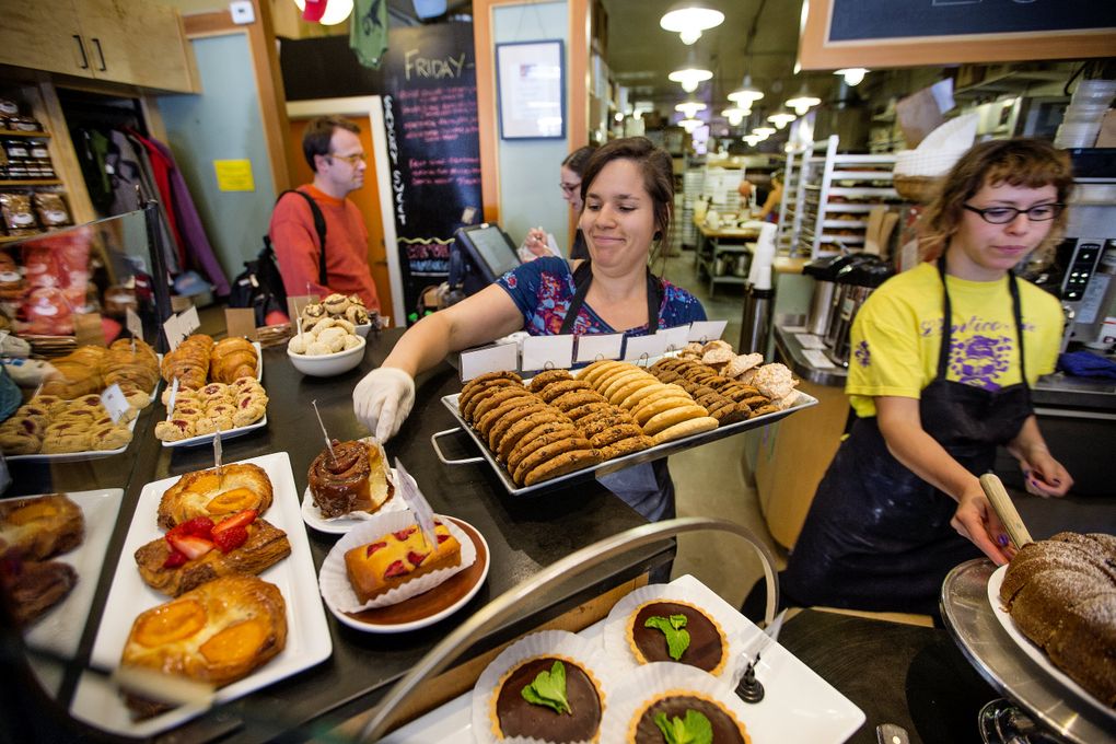 Leah Champagne puts out a tray of freshly baked cookies at Seattle’s Columbia City Bakery. The bakery, at 4865 Rainier Ave. S., makes a good side trip for cyclists riding Lake Washington Boulevard on Bicycle Sundays this summer. (Mike Siegel/The Seattle Times)