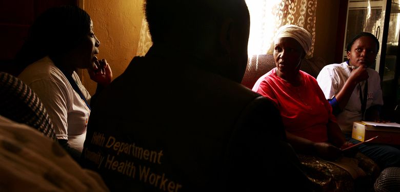 Community-engagement worker Puleng Nkase, left, talks with Zodwa Witness Mchunu in her Soweto home. Mchunu, 63, lost her adult daughter, Gloria, to AIDS. (Erika Schultz / The Seattle Times)