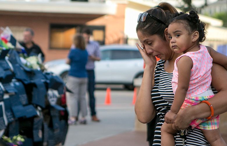 Priscilla Chavez and her daughter Kim, 1, stop by the makeshift memorial to slain officers outside the police headquarters in Dallas, July 9, 2016. At daybreak on Saturday in Dallas, the downtown streets were mostly quiet and the city seemed to be in the midst of moving from shock to a period of profound public grief after Thursday nightÕs mass shooting. (Ilana Panich-Linsman/The New York Times)