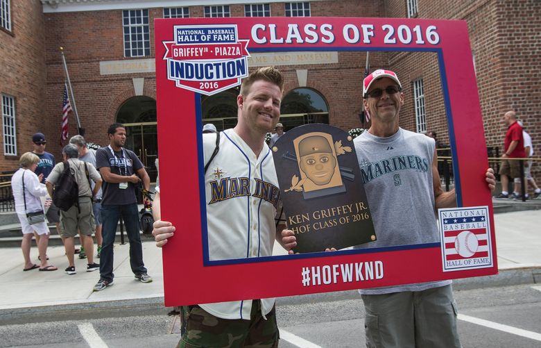 Ryan and Marc Hostetler of Seattle have their picture made outside the Baseball Hall of Fame in Cooperstown, NY, Friday – framed with a plaque of Mariner star Ken Griffey Jr. who will be inducted Sunday.  Hall of Fame weekend in Cooperstown got underway in earnest Friday with past players signing autographs, and Ken Griffey Se. on hand to talk about his son.  Photographed Jult 23, 2016.