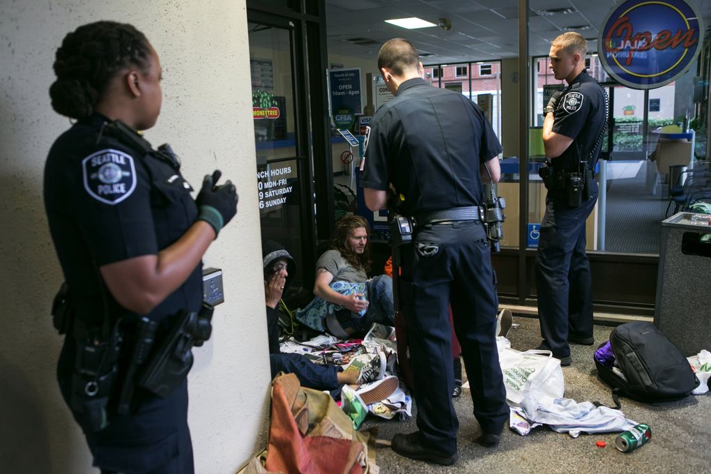 Officers Melisande Manning, Chris Couet and Jameson Mahler warn three people who have camped out in the front door of a Payday Loans office that they have to leave. (Bettina Hansen/The Seattle Times)
