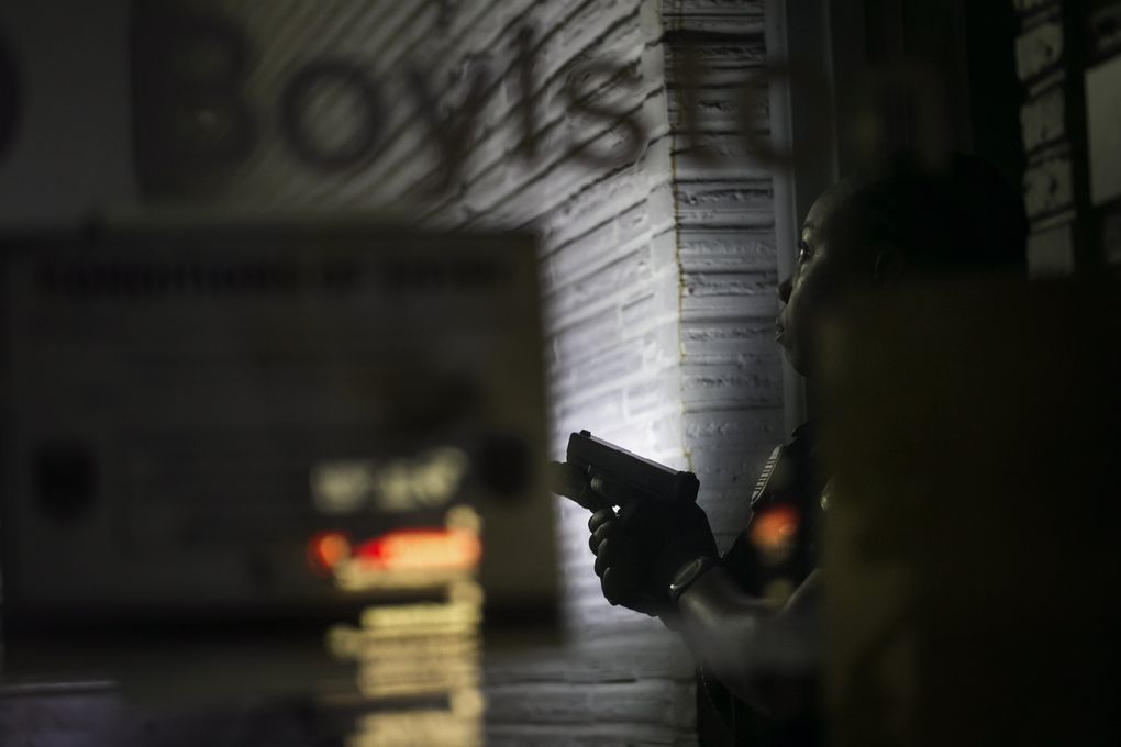 Seattle Police officer Melisande Manning keeps watch while waiting to join the search of an unoccupied building. The officers were checking a report after two people said they entered the building because they heard screams. The officers did a complete search, and found nothing. (Bettina Hansen/The Seattle Times)