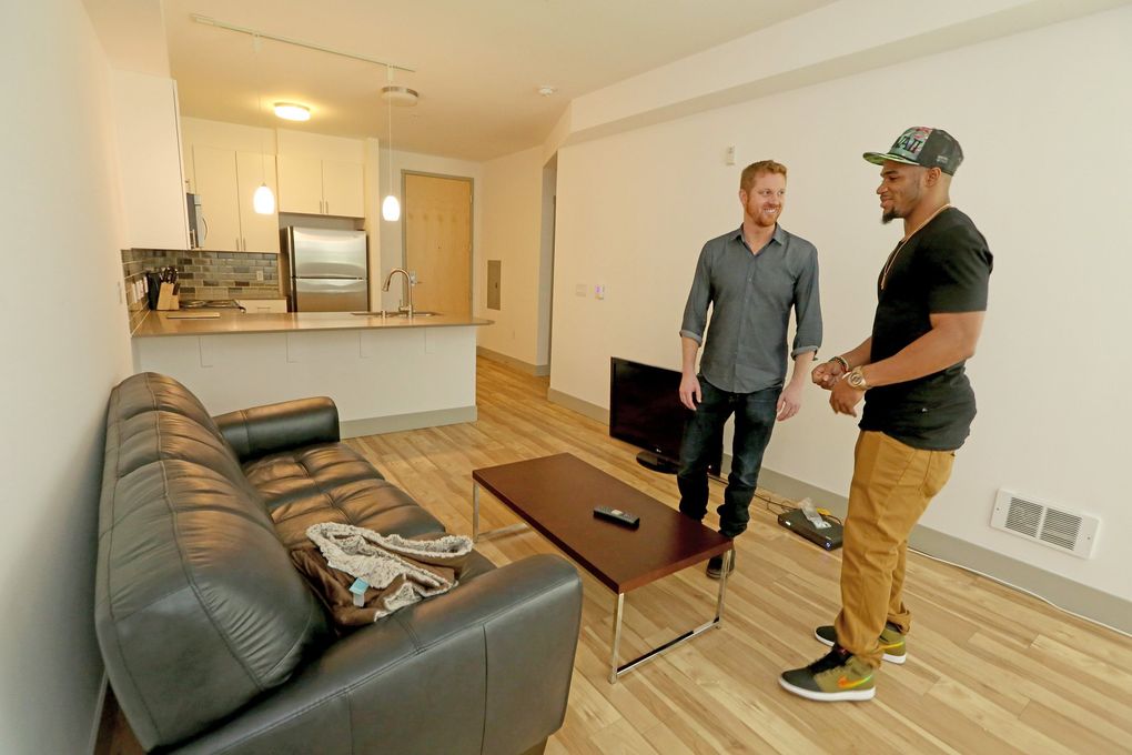 Matt Calkins, left, and Zac Brooks go over Matt’s new apartment for interior design advice. (Greg Gilbert / The Seattle Times)
