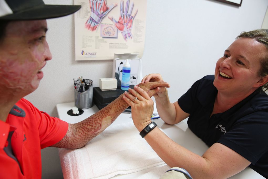 Daniel Lyon Jr. jokes with hand therapist Jennifer Helmer. She says he’s making good progress, although his right hand is still far less flexible than his left. (Ken Lambert/The Seattle Times)