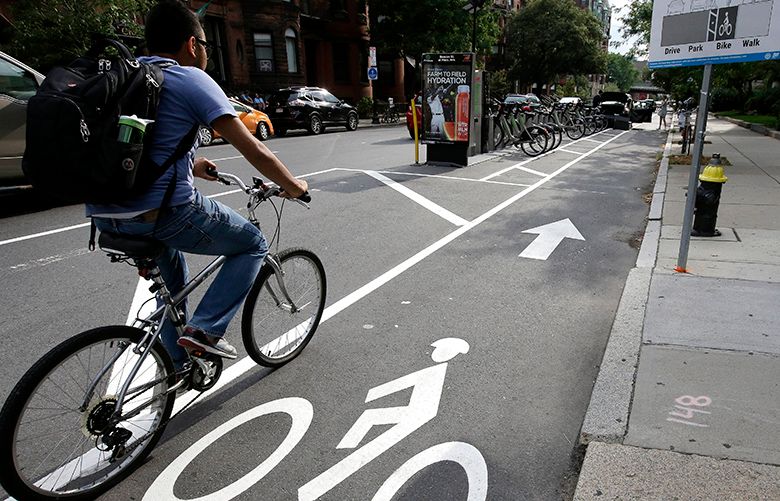 In this Tuesday, Aug. 16, 2016, photo, a cyclist enters a bike lane that is routed between parked cars and the sidewalk in Boston. Cities around the world are increasingly changing bike lanes to make them safer in light of fatal crashes involving cyclists and cars. (AP Photo/Steven Senne) MASR202