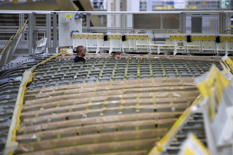 Employees work on the massive composite wings for the A350 jetliner at a state-of-the-art Airbus plant in Broughton, north Wales. (Jon Super / Special to The Seattle Times)