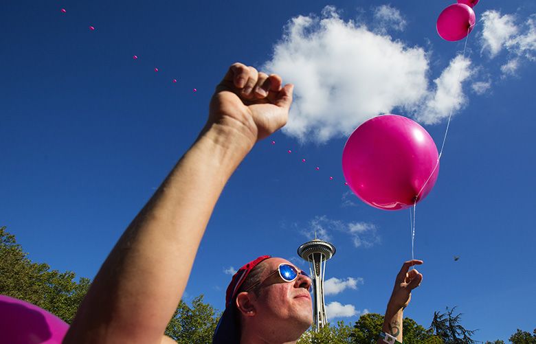 Sean T. Hanratty holds onto Balloonchain, an art piece that consists of 80 helium-filled balloons that reach up to 600 feet in the air, at the annual Bumbershoot music festival at the Seattle Center, Saturday, September 3, 2016.
