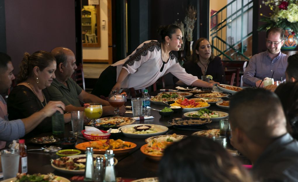 Genny Villa, manager of the Xochimilco Tequila Bar and Restaurant in Yakima, serves lunch to Hispanic community leaders meeting with the new Mexican consul in Seattle. She and her sister, Dania, are “Dreamers,” meaning they came here as children and now have legal status via the Deferred Action for Childhood Arrivals (DACA) program. They are not able to vote but are paying attention to the presidential election and immigration policy as changes could affect them. (Bettina Hansen/The Seattle Times)