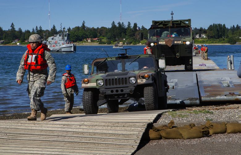 As part of the Cascadia rising drill, after a causeway ferry lands at the beach at Jensen Point on Vashon Island and after a track was laid down, vehicles and Washington National Guard troops drive or walk onto the island Monday, June 6, 2016.  They were simulating the delivery of supplies and troops if ferry terminals are destroyed during a huge earthquake.