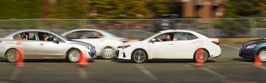 On the stunt course, students practice precision driving skills as one car drives in reverse with two others close behind and another passing. (Benjamin Benschneider/The Seattle Times)