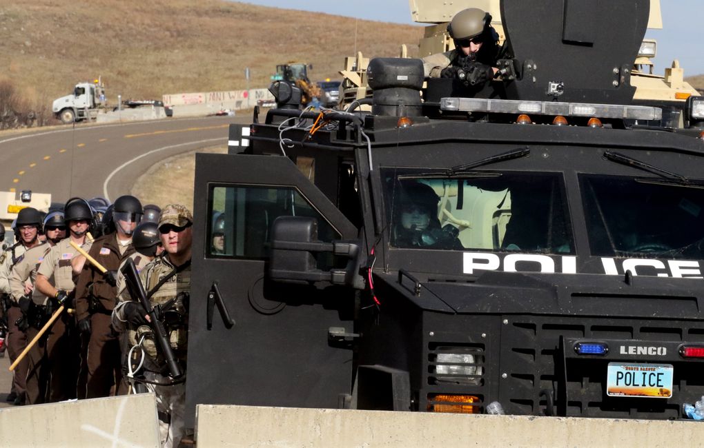Police and deputies from many counties and states mass on the other side of the barricaded bridge on Highway 1806 just north of the main encampment on Friday. (Alan Berner/The Seattle Times)