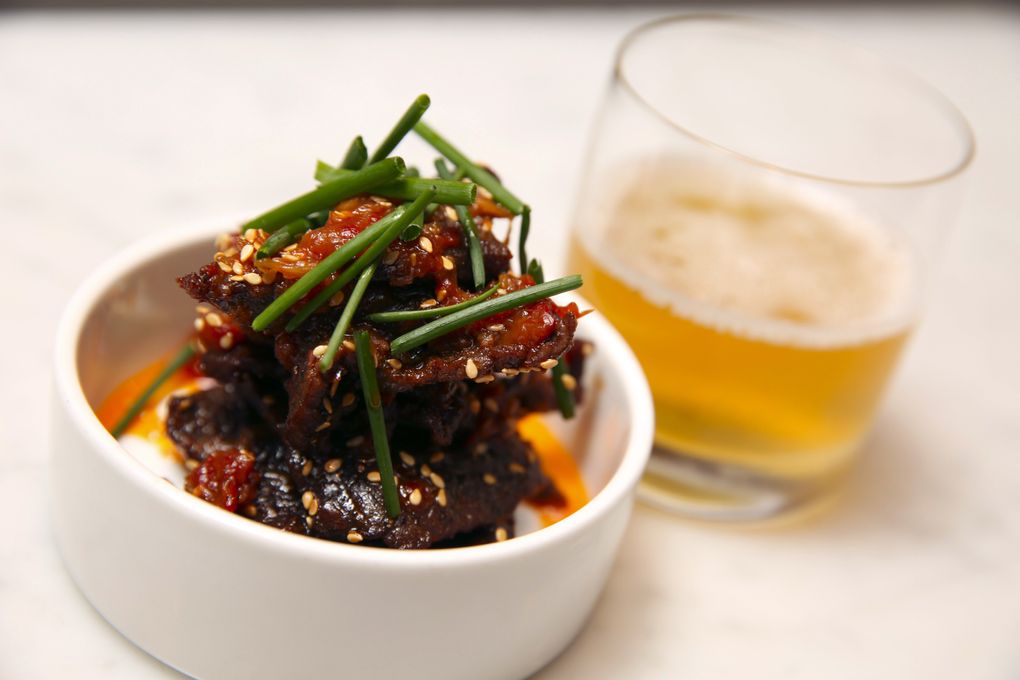 A snack at Heartwood Provisions: wagyu “beef jerky” glazed with a sweet-hot chile preserve, paired with a ale and dry vermouth cocktail. (Ken Lambert/The Seattle Times)