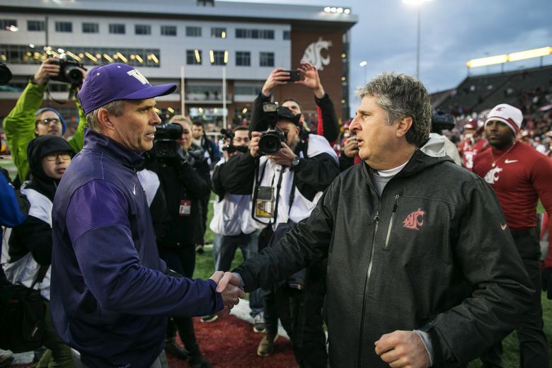 Washington Huskies head coach Chris Petersen, left, shakes hands with Washington State Cougars head coach Mike Leach after the game. The Huskies won 45-17.  (Johnny Andrews / The Seattle Times)