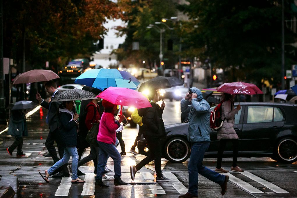 Pedestrians make their way around downtown Seattle on a rainy night this fall. (Erika Schultz/The Seattle Times)