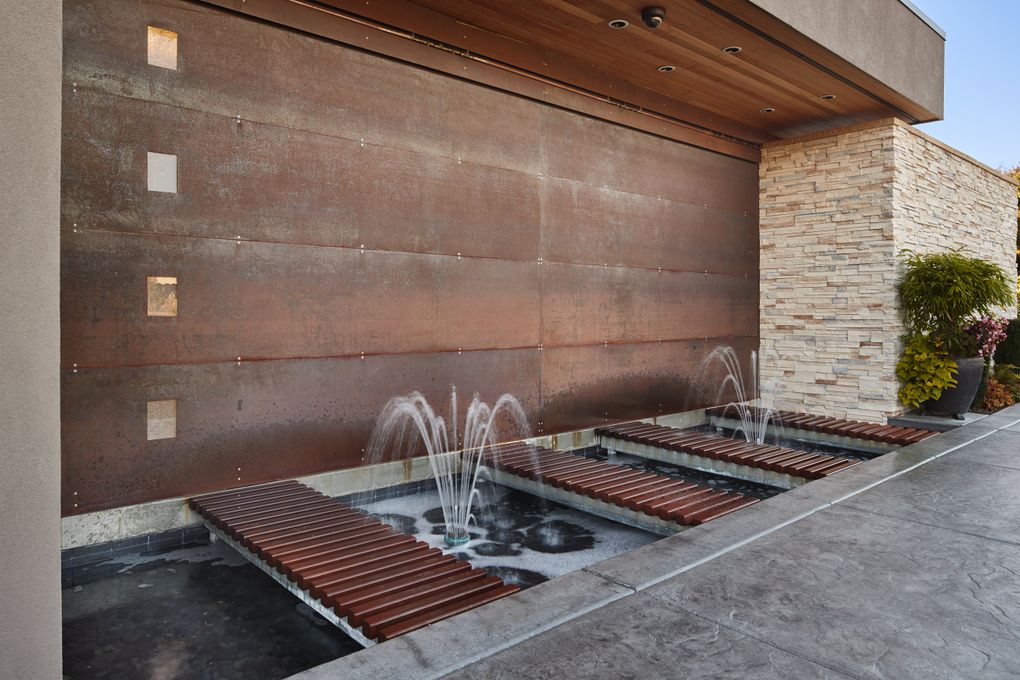 Customized COR-TEN steel entry ramps lead over a fountained moat to the Nelsens’ garage, a hefty 22-foot-span of more COR-TEN that’s raised and lowered by a hydraulic pumping station. (Benjamin Benschneider/The Seattle Times)