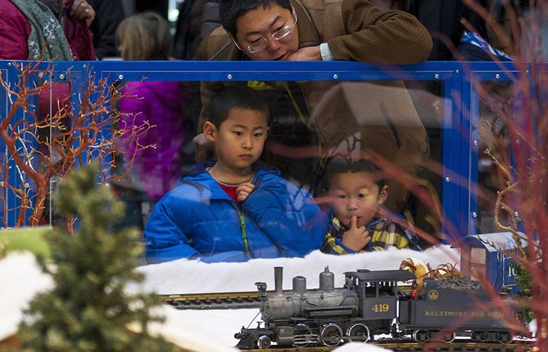 Father Kia Wong talks to his sons Nathaniel, 5, and David, 4, as a model train passes by during the annual Winterfest celebration on Saturday, December 10, 2016, at the Seattle Center.