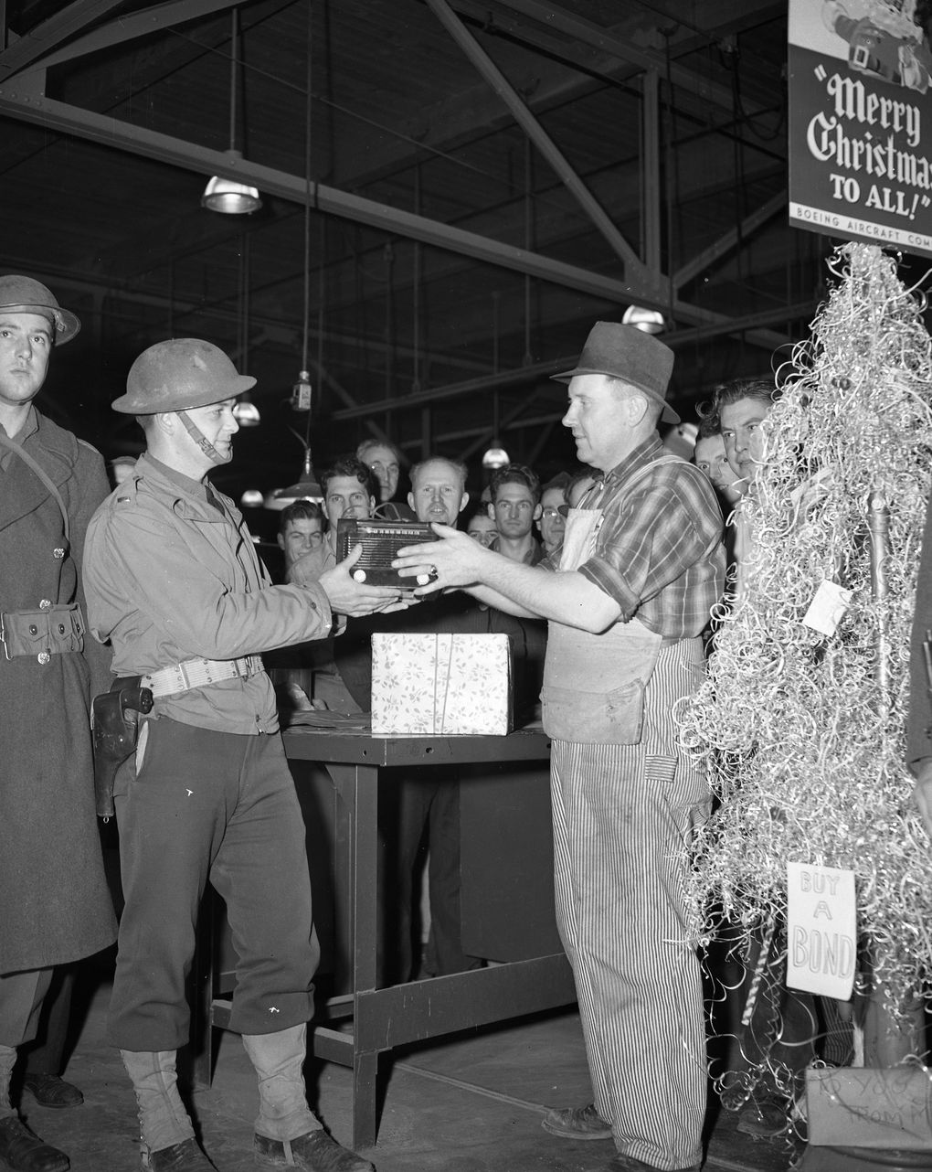 In December 1941, Frank Beidler of the Boeing wood shop presents a radio to Lt. Alvin Gannon. The employees in the wood shop gave two radios to the soldiers guarding the plant.The Christmas tree was made from metal scraps and shavings. (The Boeing Company)