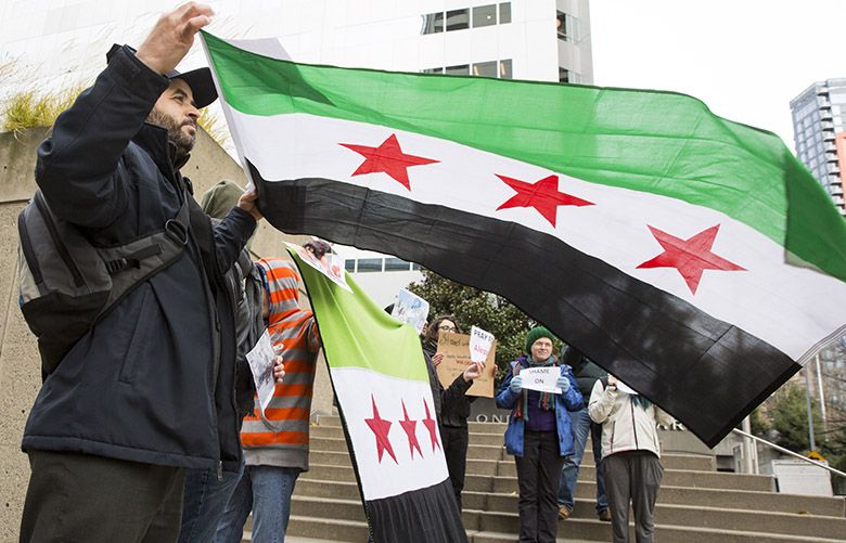 Recent Syrian refugee Mustafa al Mustafa flies his country’s flag with other Syrians and supporters standing outside One Union Square, the building in downtown Seattle where the Consulate General of Russia is located Wednesday December 14, 2016. They peacefully demonstrated with signs saying “Pray for Aleppo,” and chose their location in response to Russia, a Syrian ally. News reports say that the shelling of civilians and rebel fighters continues Wednesday in East Aleppo, pushing back planned evacuations. The Seattle group plans to demonstrate Thursday, maybe Friday and over the weekend.