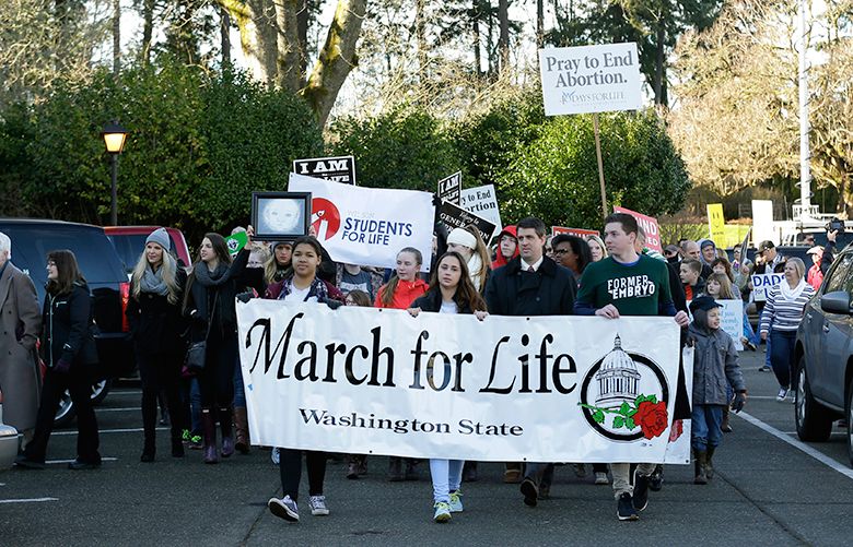 Participants in an anti-abortion rally and march carry signs and banners as they arrive at the Capitol in Olympia, Wash., Monday, Jan. 23, 2017. (AP Photo/Ted S. Warren)