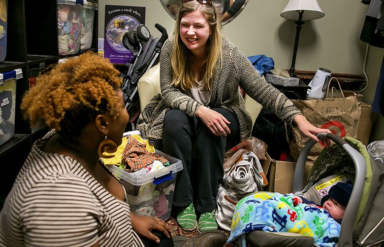 Suzanne Brewer Melchor, center, and her son, Mateo Melchor Brewer, 3 months, are greeted by outreach birth doula Rokea Jones, left, in the baby boutique room at Open Arms Perinatal Services in the El Centro De La Raza building on Thursday, January 12, 2016, in Seattle. Melchor stopped by the office to get advice from the doulas and personnel at the center.

(*NOTE: THE SON’S LAST NAME IS INDEED REVERSED FROM HOW THE MOTHER LISTS HER NAME *)