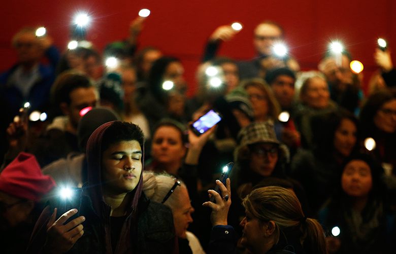 Kai Schmidt closes his eyes as he and others hold up flashlights and cellphones during The Ghostlight Project event held outside of the Seattle Repertory Theatre in Seattle Center on Thursday, January 19, 2016. Inspired by the tradition of leaving a “ghost light” on in a darkened theater, artists and communities will make pledge to stand for and protect the values of inclusion, participation, and compassion for everyone regardless of race, religion, immigration status, gender identity, or sexual orientation.