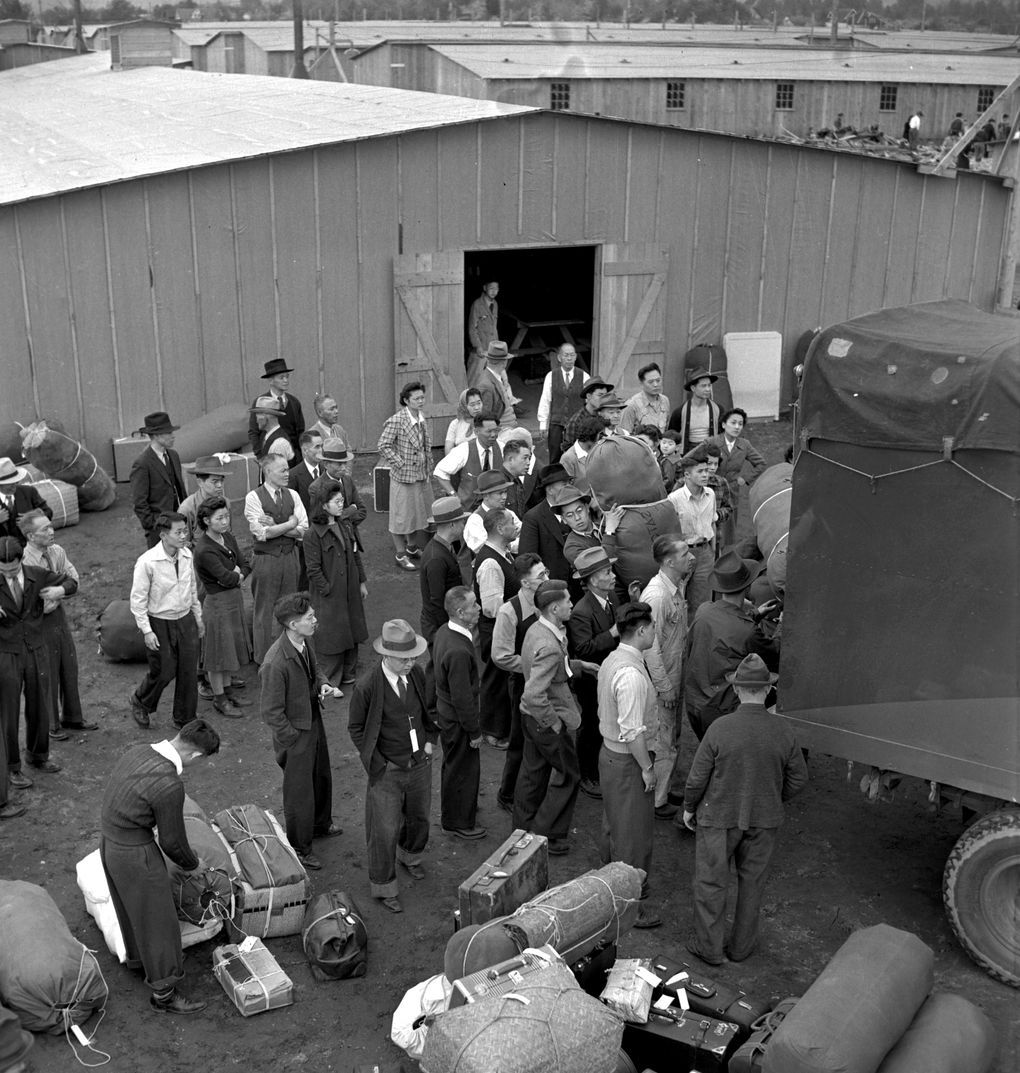 People of Japanese descent, relocated from the Seattle area, unload their belongings as they arrive at the Washington state fairgrounds in Puyallup in April 1942. It was used as a temporary assembly center until internees could be taken to other camps. (PAUL WAGNER/AP)