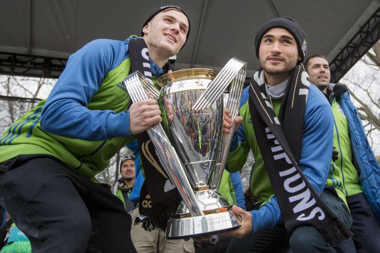 Mercer Island native Jordan Morris and his “bestie,” University of Washington alum Cristian Roldan, hoist the MLS Cup at the Sounders’ victory rally at the Seattle Center in December. (Bettina Hansen/The Seattle Times)