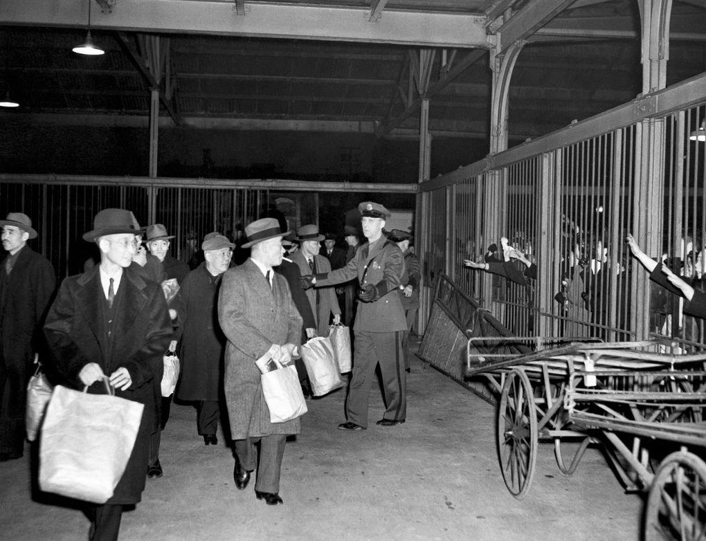 Carrying belongings in paper bags, internees leave Seattle by train for Fort Missoula, Montana, on March 19, 1942, as relatives wave through bars. A group of 150 internees had been held in the Seattle immigration station. (AP)