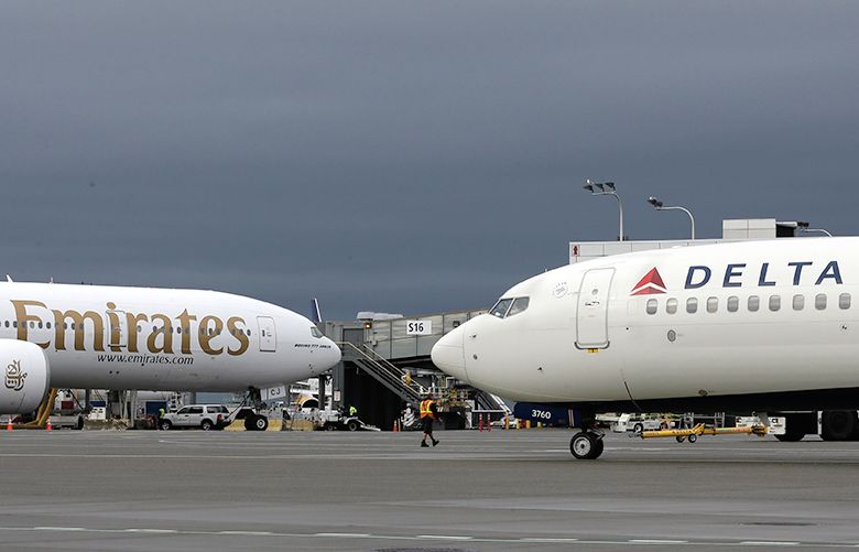 Airplanes belonging to Emirates, left, and Delta Air Lines, right, are shown Tuesday, Jan. 26, 2016, at Seattle-Tacoma International Airport in Seattle. (AP Photo/Ted S. Warren)