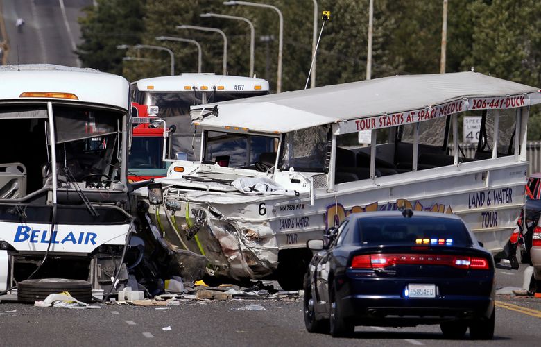 FILE – In this Sept. 24, 2015, file photo, a “Ride the Ducks” amphibious tour bus, right, and a charter bus remain at the scene of a multiple fatality collision on the Aurora Bridge in Seattle. With an ability to travel by both land and sea, duck boats have long been tourist attractions for sightseers around the U.S. A spate of deadly accidents has forced safety improvements and has prompted some to call for a total ban on the vehicles. (AP Photo/Elaine Thompson, File) BX401 BX401