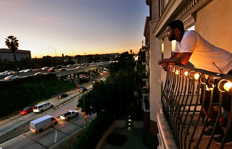 Everett Smith, a renter at the Orsini apartments, looks out from his balcony at rush hour traffic on the 101 and 110 freeway interchange in downtown Los Angeles, Calif. (Don Bartletti/Los Angeles Times/TNS)