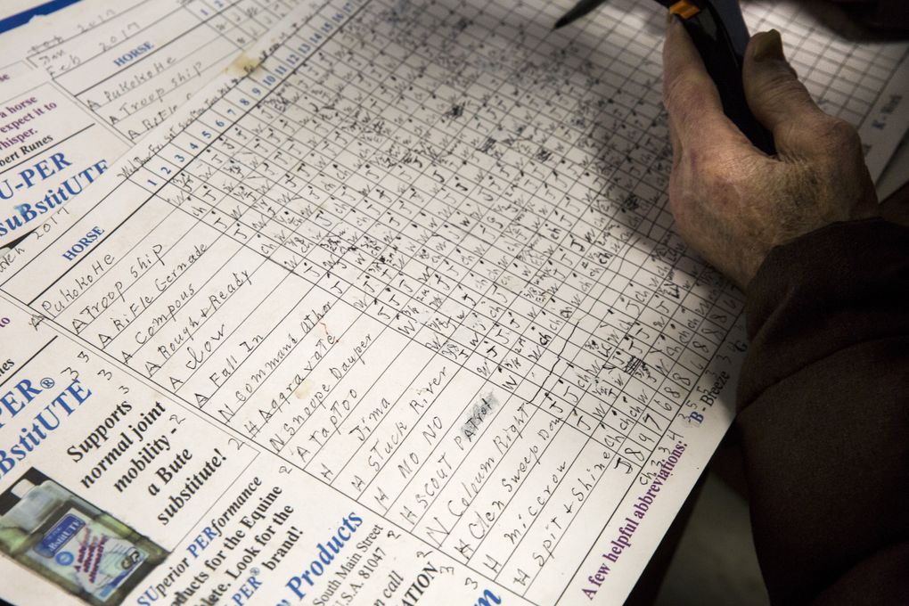 Munger goes over his charts with a magnifying glass in his office in the stables. (Bettina Hansen/The Seattle Times)