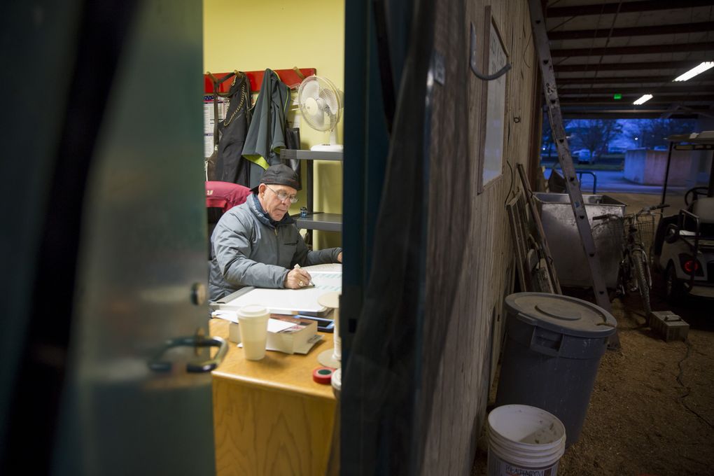 Dennis Snowden, assistant trainer for Frank Lucarelli, works out the schedule for his busy day at dawn in his office at the stables at Emerald Downs. (Bettina Hansen/The Seattle Times)