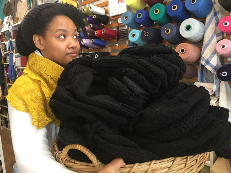 Jessica Owens holds a basket of black beanies that she and volunteers knitted and crocheted for the Black Lives Matter march Saturday in downtown Seattle. She works at The Weaving Works in Seattle.  (Cory Rice)