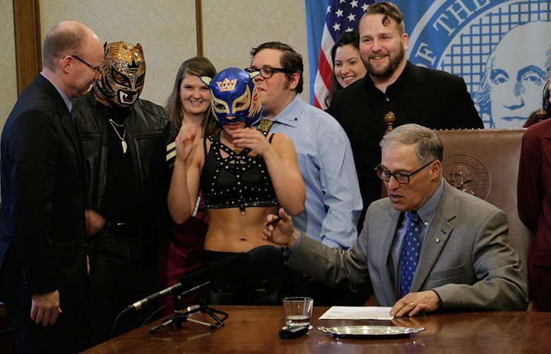 Washington Gov. Jay Inslee talks with supporters of theatrical wrestling before signing a bill that creates a license for theatrical wrestling schools, on Monday, April 17, 2017 in Olympia, Wash. Under the measure, any licensed theatrical wrestling school would be allowed to schedule a certain number of public performances. (AP Photo/Rachel La Corte)