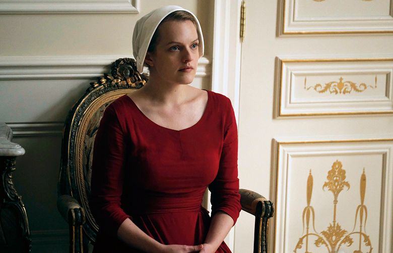 This image released by Hulu shows Elisabeth Moss as Offred in a scene from, “The Handmaid’s Tale,” premiering Wednesday on Hulu with three episodes. The remaining seven hours will be released each Wednesday thereafter. (George Kraychyk/Hulu via AP)