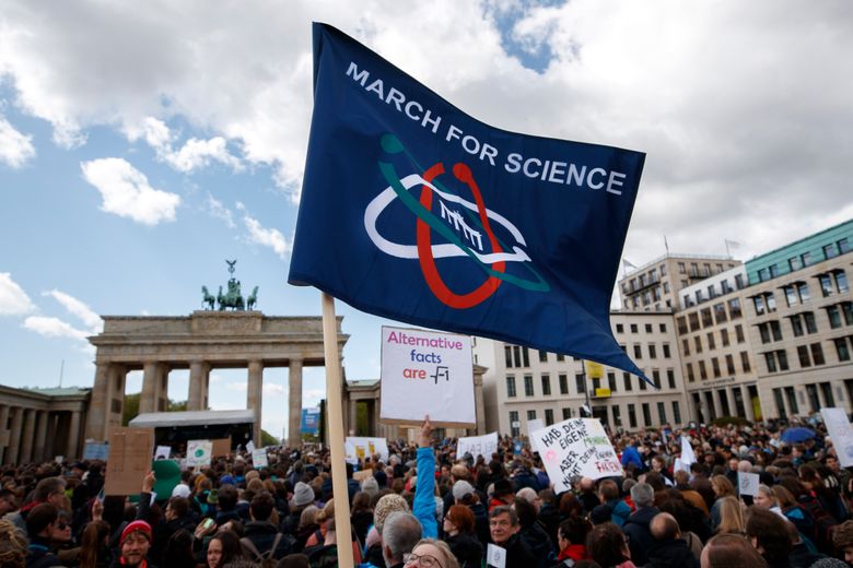 epa05921060 A man waves a flag during the gathering following the March for Science in Berlin, Germany, on 22 April 2017. Hundreds of thousands of people in more than 400 locations across the globe are taking part in the March for Science to recognise scientific progress, raise awareness of scientific discovery, and defend scientific integrity.  EPA/CARSTEN KOALL