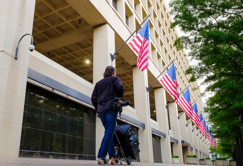 A member of the news media walks in front of the FBI headquarters building early in the morning in Washington, Wednesday, May 10, 2017. President Donald Trump fired FBI Director James Comey Tuesday evening. (AP Photo/J. David Ake)