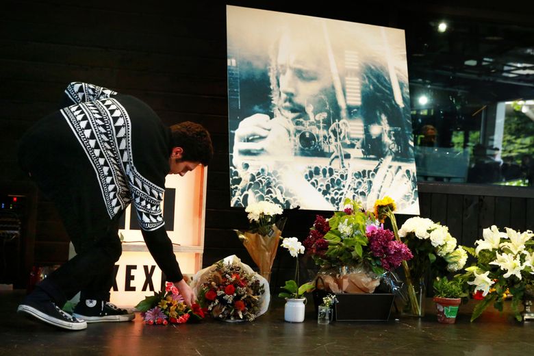 Julian Anderson, a Seattle resident, places flowers on a memorial as crowds gather to remember Chris Cornell at the KEXP studio at Seattle Center Thursday, May 18, 2017. Cornell, who was born in Seattle and shaped the local music scene, died at the age of 52 Wednesday night in Detroit. “Chris Cornell has had a big impact on my life,” says Anderson.  (Erika Schultz/The Seattle Times)