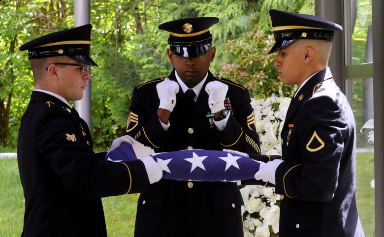Staff Sgt. Alvin Proby, center, prepares to receive the flag from Zach Berg, left, and Jeremy Hernandez before presenting it to Sylvia Scherer, who said the memorial service on Wednesday was “absolutely beautiful.”  (Alan Berner/The Seattle Times)