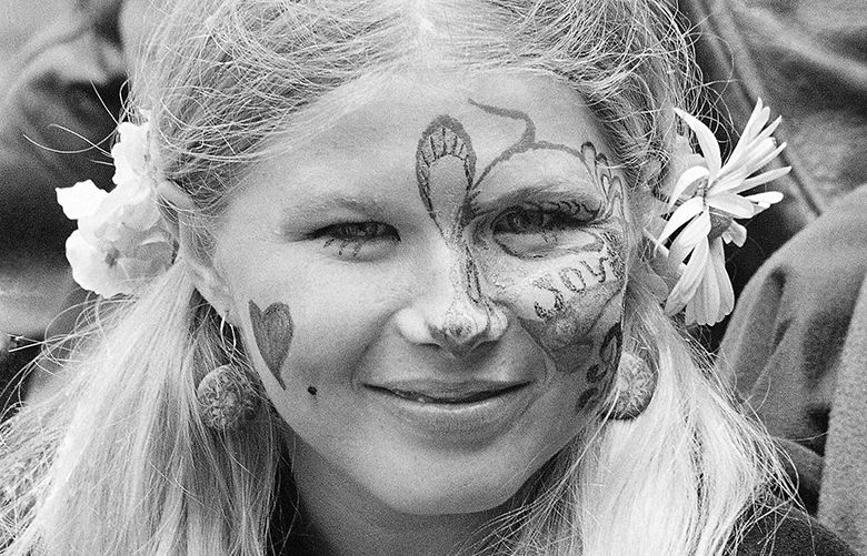 ADVANCE FOR USE TUESDAY, JUNE 13, 2017 AND THEREAFTER-FILE – In this Thursday, June 21, 1967 file photo, Judy Smith, wearing face paint and flowers in her hair, smiles as she and others gather at Golden Gate Park in San Francisco. Fifty years ago, throngs of American youth descended on San Francisco to join a cultural revolution. (AP Photo/Robert W. Klein, File)
