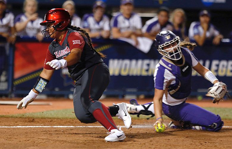 Oklahoma’s Fale Aviu avoids the tag of Washington’s Morganne Flores on a squeeze bunt in the second inning of a Women’s College World Series softball game in Oklahoma City, Friday, June 2, 2017. (Sarah Phipps/The Oklahoman via AP) OKOKL325 OKOKL325