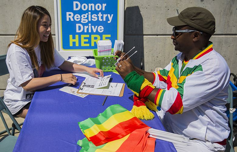 Mekonnen Desta, right, takes q tips from Henna Park, left, intern with Be The Match, to swab his mouth for protein samples on Friday, July 7, 2017 at the Be The Match bone marrow drive outside Renton Memorial Stadium. The samples will be tested to see if Desta matches with someone in need of a marrow transplant.