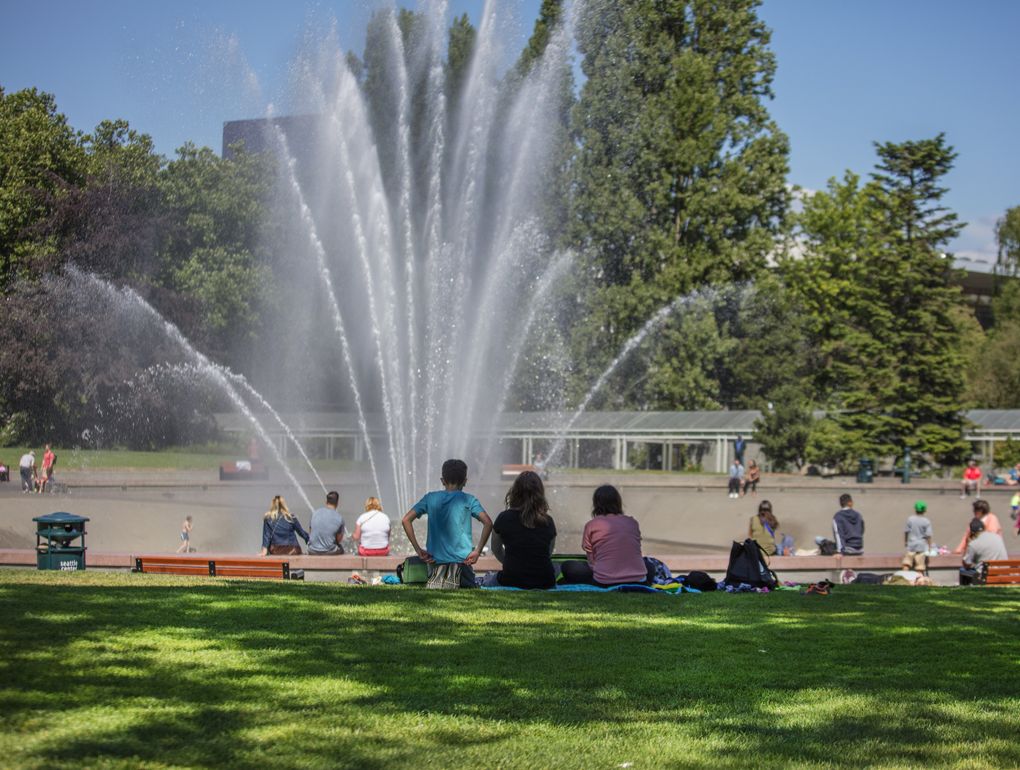 People gather around the International Fountain at Seattle Center, which treats its hardscapes and other areas with an average of 130 gallons of solutions containing pesticides each year. (Steve Ringman/The Seattle Times)