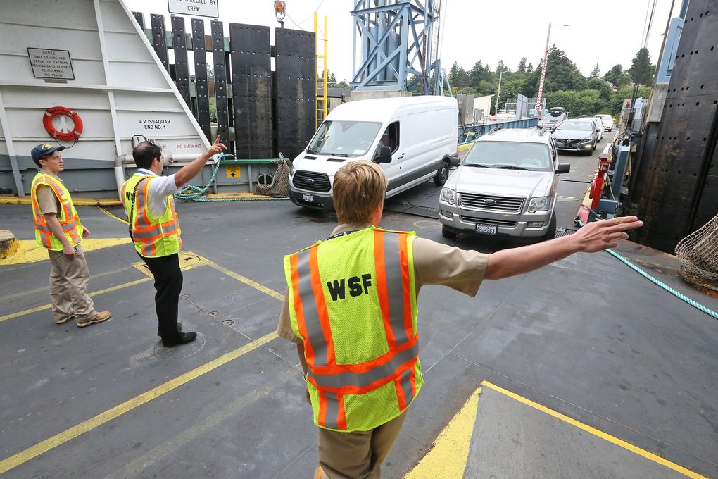 On the car deck of the Issaquah, interns John Bresnahan, left, and Sebastian Jewell, right, direct traffic with the help of ferry veteran Ben Berke, center. (Greg Gilbert/The Seattle Times)