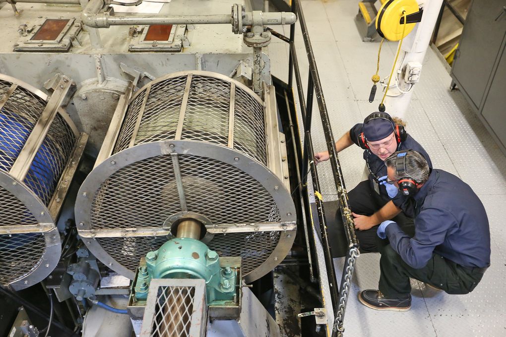 Below deck in the engine room of the Cathlamet, veteran oiler Kyle Peck, top, explains details of the machinery to intern Marshall Scott Warner. (Greg Gilbert/The Seattle Times)