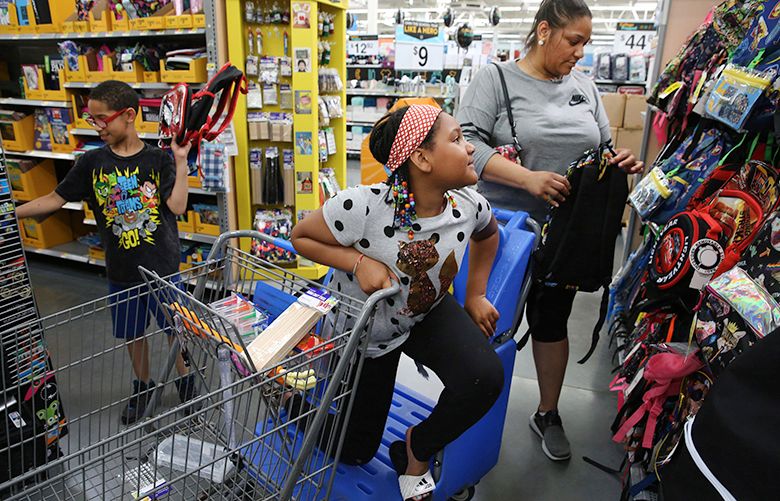 Lavinia Johnson, with her children Micah Blanks, 11, and Brooklyn Banks, 10, shops for back-to-school supplies recently at Wal-Mart in Chicago. Many shoppers are opting for discount stores over department stores.  (Nuccio DiNuzzo/TNS)