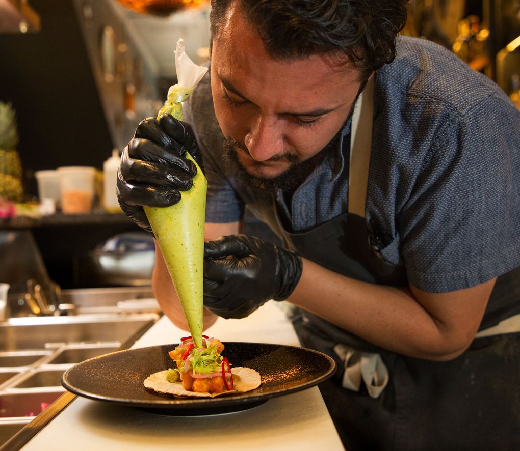 Chef Felipe Prieto builds a fish taco on a corn tortilla made from scratch at Dead Line in Pioneer Square. (Mike Siegel / The Seattle Times)