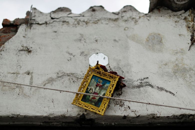 In this Saturday, Sept. 23, 2017 photo, a framed image of a religious icon hangs precariously on a cracked wall of the Santiago Apostol church destroyed during the recent 7.1-magnitude earthquake, in Atzala, Mexico. Little remains of the golden yellow church with a red roof where a child’s baptism turned into tragedy when the roof of a church collapsed as the powerful earthquake shook central Mexico. Eleven members of a family died, including the 2-month-old girl being christened. (AP Photo/Natacha Pisarenko)