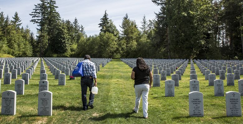 Lourdes Reyes, right, and her husband, Mario San Agustin, visit her son’s gravesite at Tahoma National Cemetery in Kent. (Bettina Hansen/The Seattle Times)